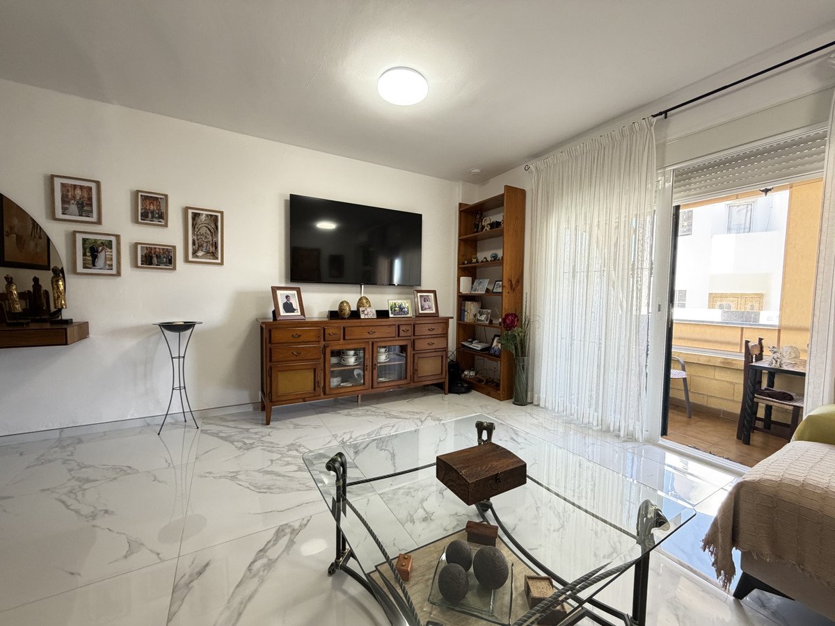 Living room with marble floor, TV, and sliding door to balcony