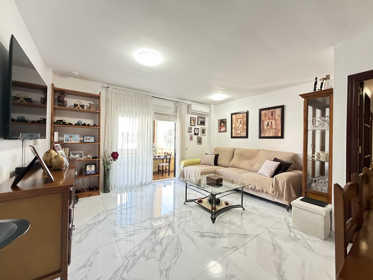 Spacious living room with marble floor, beige sofa, and sliding glass doors to balcony