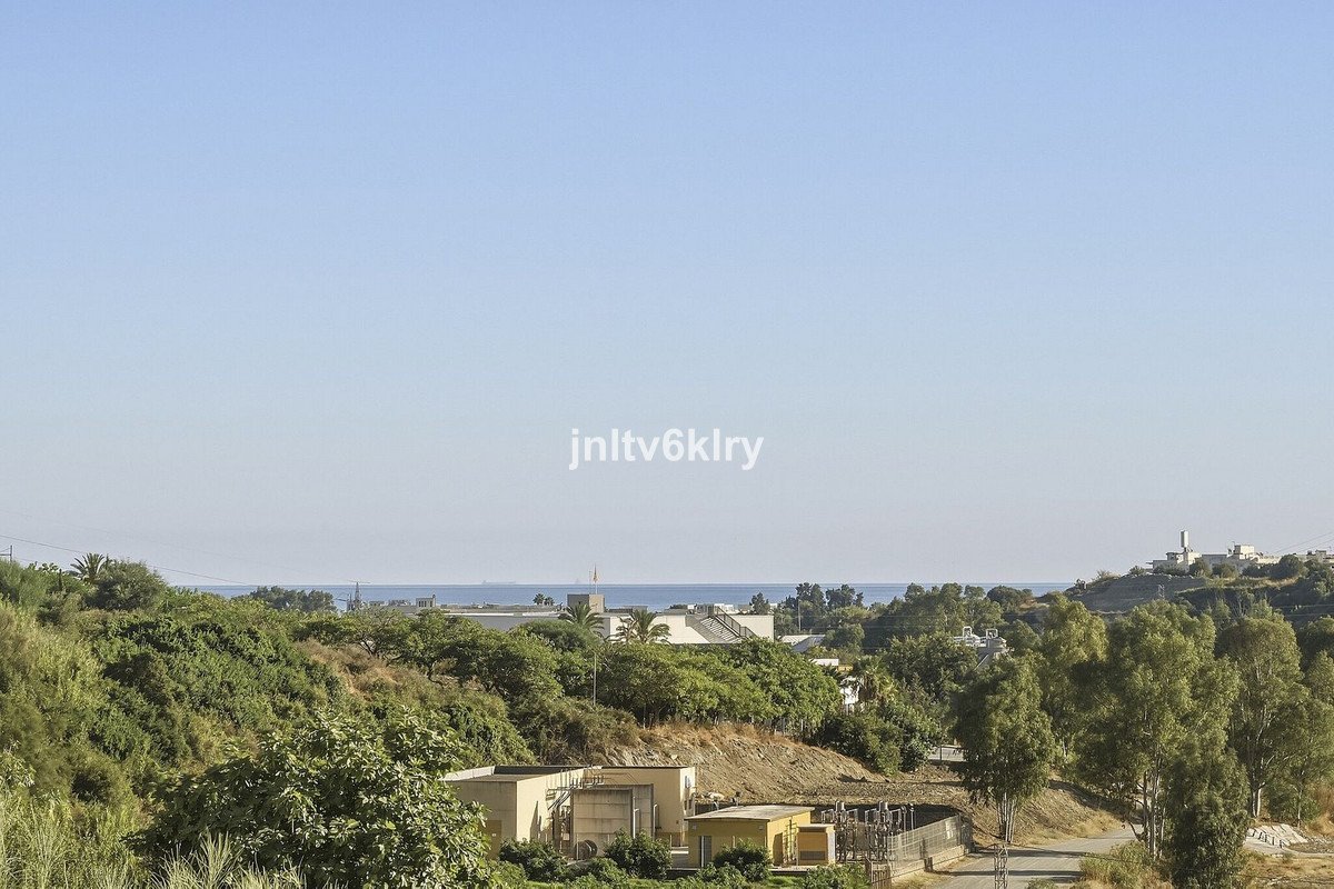 Distant view of the sea and landscape with trees and buildings under a clear blue sky.