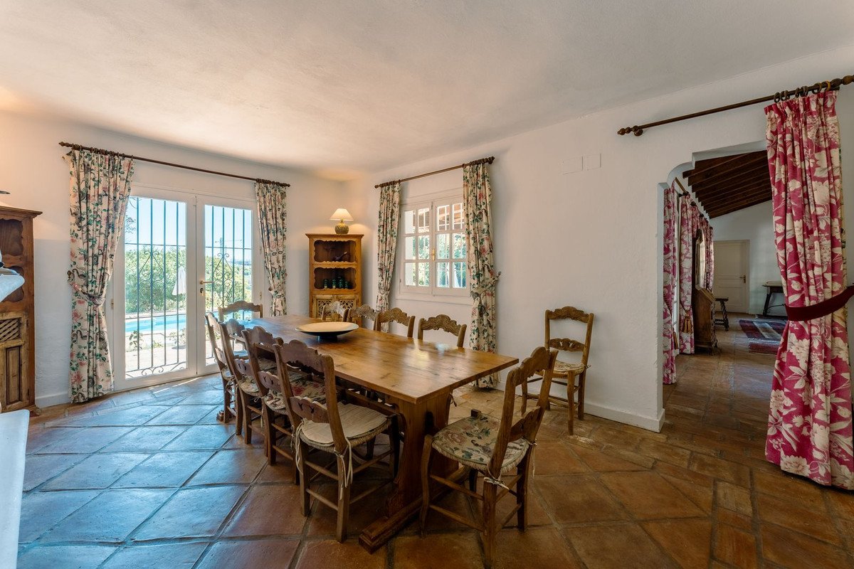 Spacious dining room with a large wooden table, chairs, and a view of the pool through French doors.