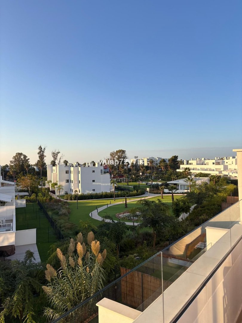 Balcony view of modern condos with landscaped gardens and clear blue sky.