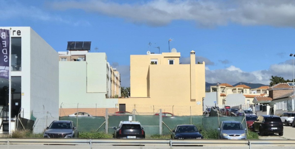Several modern residential buildings with cars parked in front and a clear blue sky overhead.