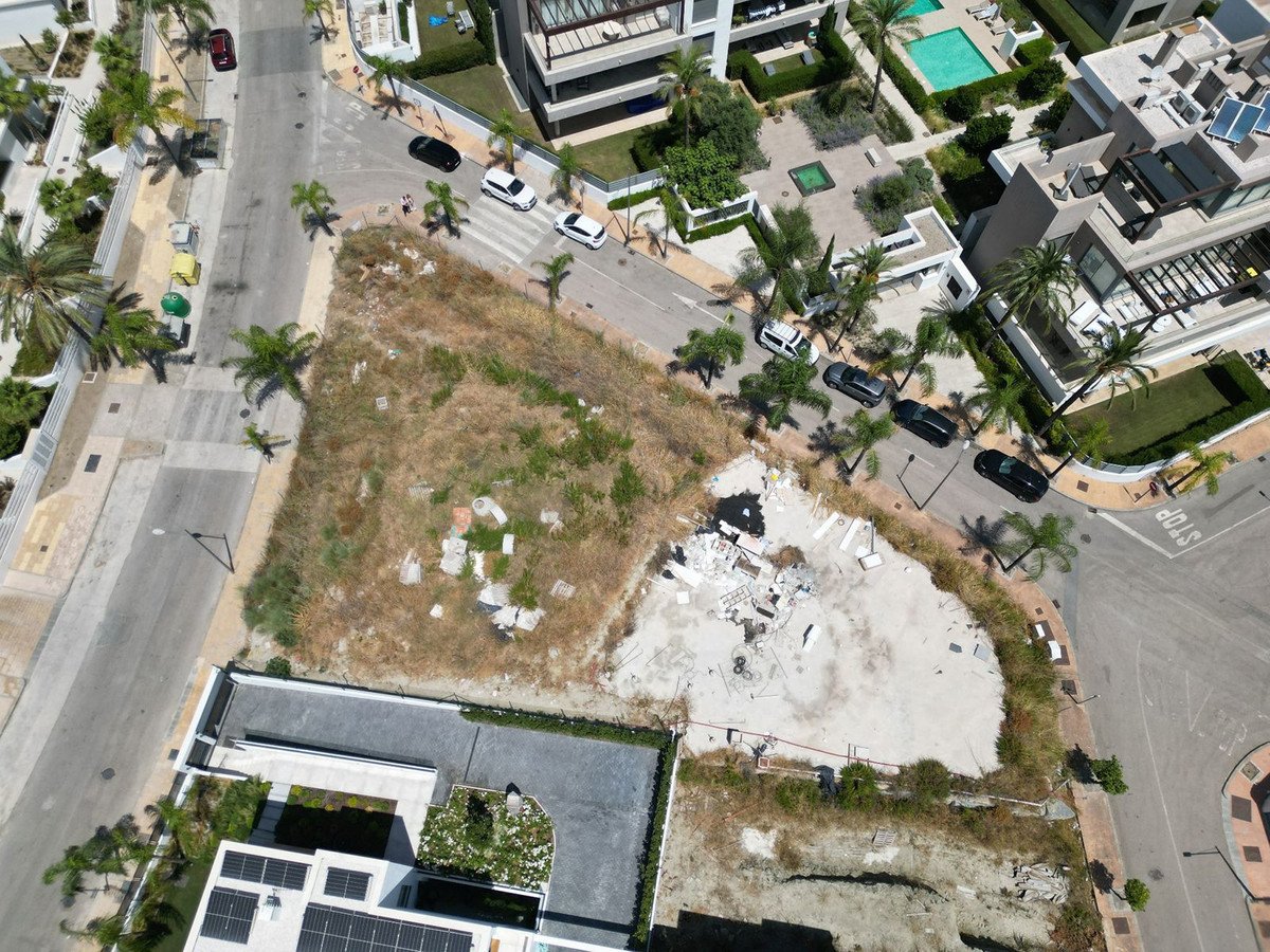 Aerial view of an empty lot with overgrown grass and construction debris in an urban area