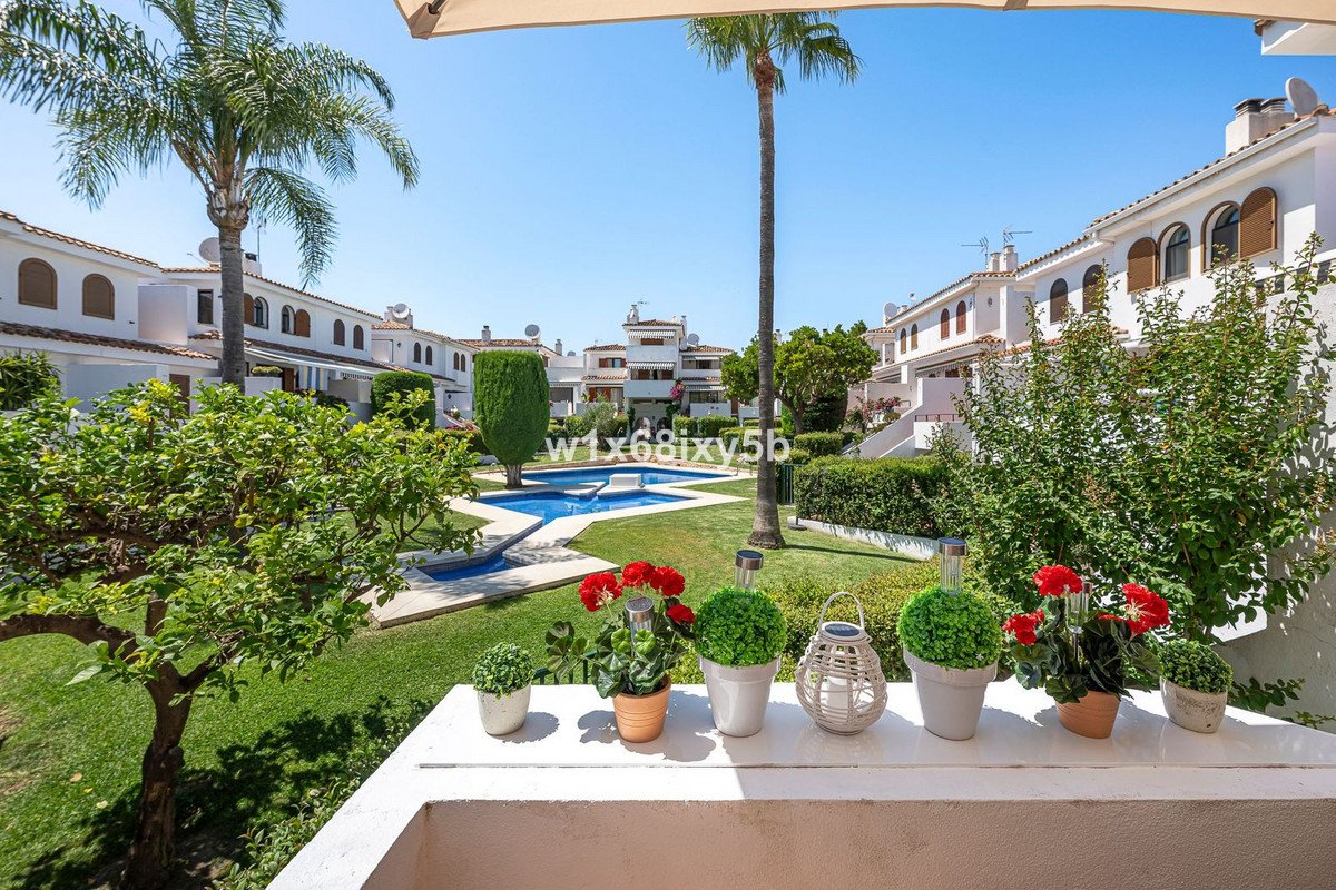Patio with potted flowers overlooking a communal pool and palm trees