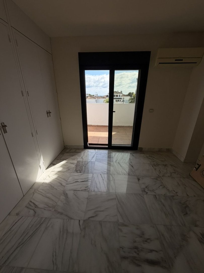 A bedroom with marble floors, large built-in closets, and a sliding glass door leading to a terrace with town views.
