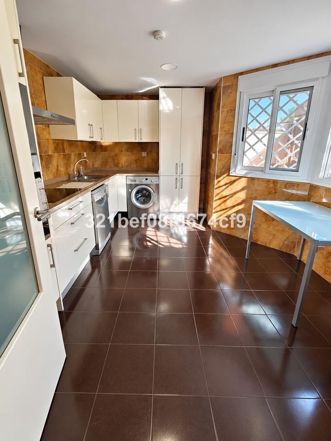 Modern kitchen with white cabinets, stainless steel appliances, and a window overlooking a sunny outdoor area.