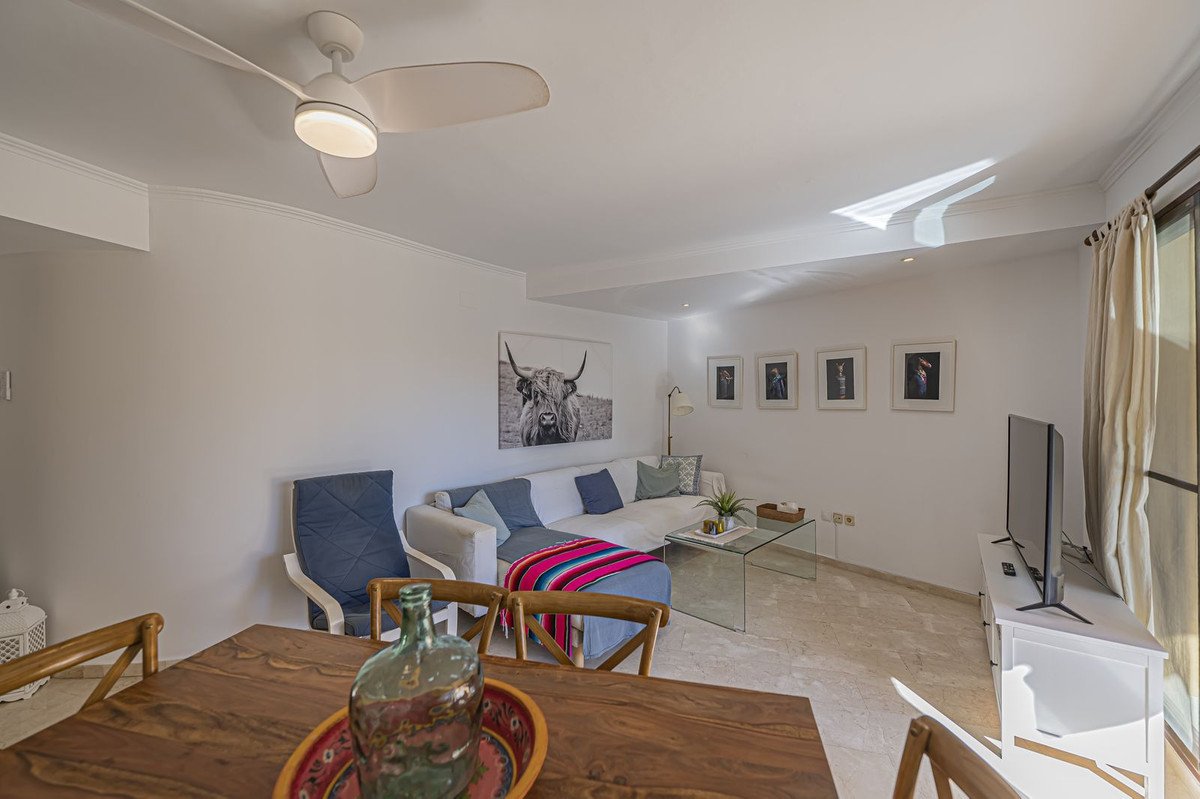 Living room with white sofa, blue cushions, dining table, and ceiling fan.