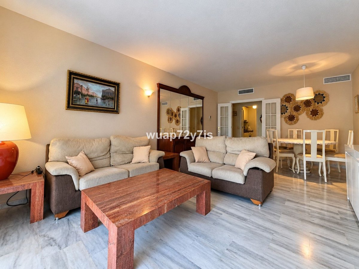 A spacious living and dining area with comfortable sofas, a large coffee table, and a dining set, featuring warm lighting and elegant decor.