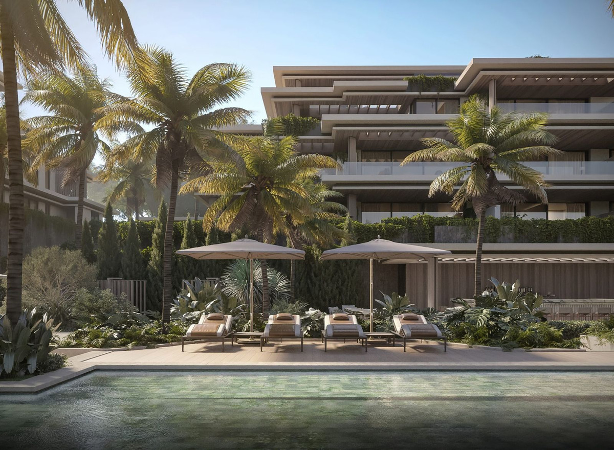 Luxe Essence Residence zwembad met ligstoelen en palmbomen.