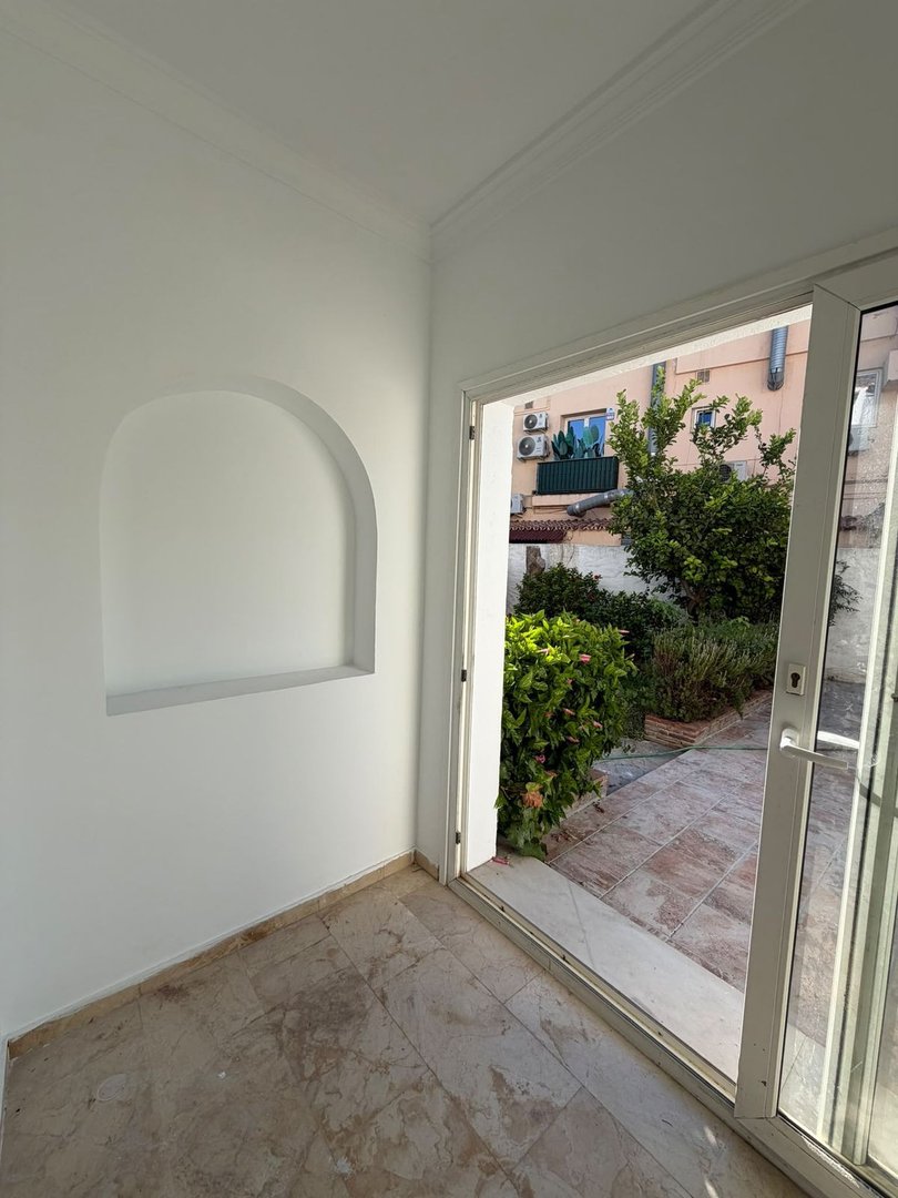 Living room with arched niche and sliding glass door to patio with greenery