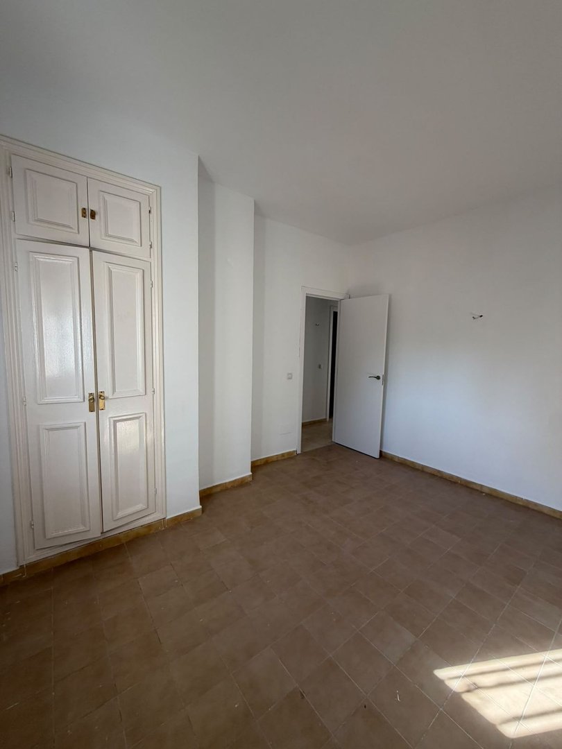 Empty room with white walls, tiled floor, and built-in cabinets