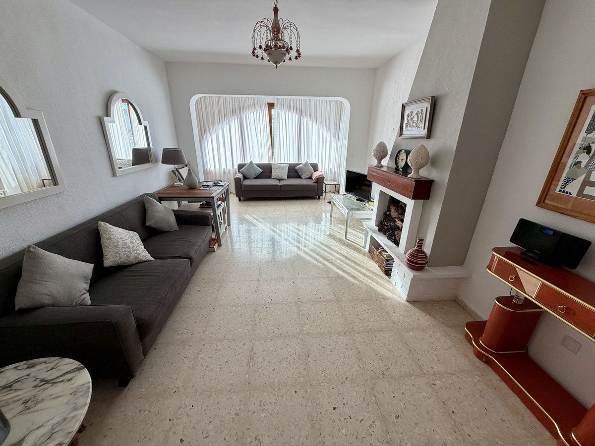 Spacious living room with a fireplace, comfortable sofas, arched windows, and decorative mirrors.