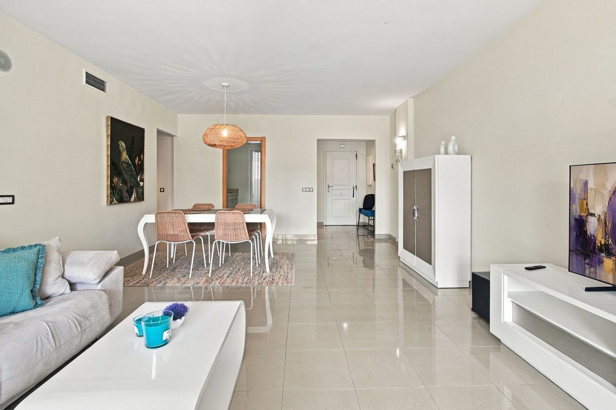 Modern living and dining area with light walls, comfortable sofa, dining table, and contemporary artwork.