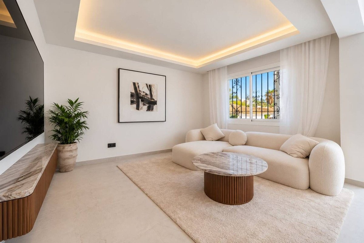 Modern living room with a plush sectional sofa, contemporary coffee table, and a large window showing an outdoor view.