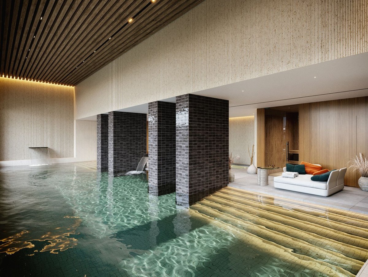 Luxurious indoor swimming pool with a cascading waterfall, modern lounge area with white sofa, and tranquil ambiance.