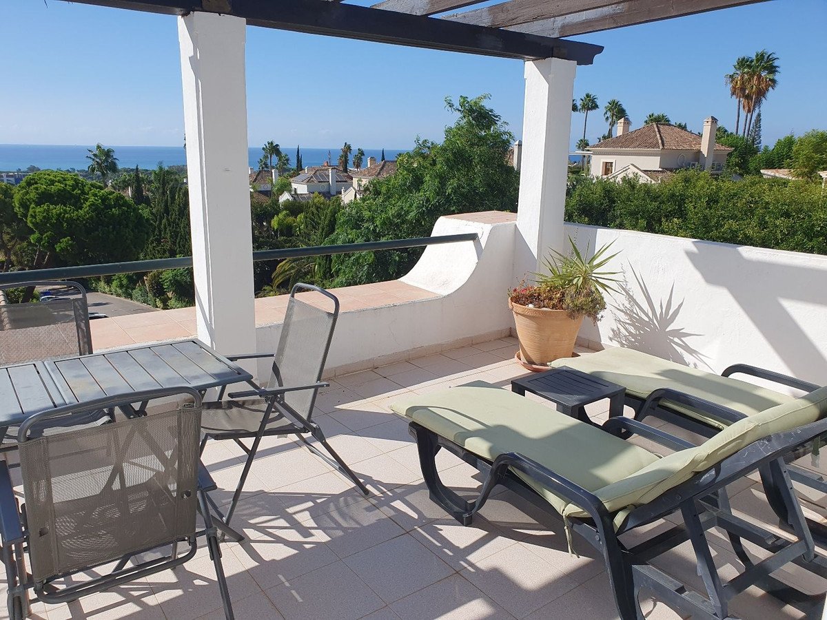Terrace with lounge chairs, table and chairs, offering a sea view and surrounding greenery.