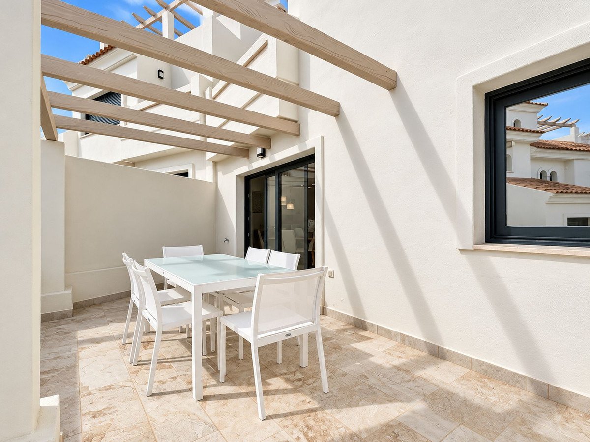 Outdoor patio with white dining table and chairs under wooden pergola
