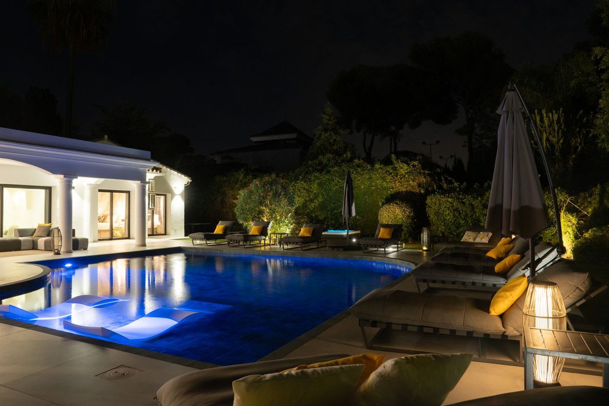 Luxury villa with illuminated swimming pool and outdoor lounge at night
