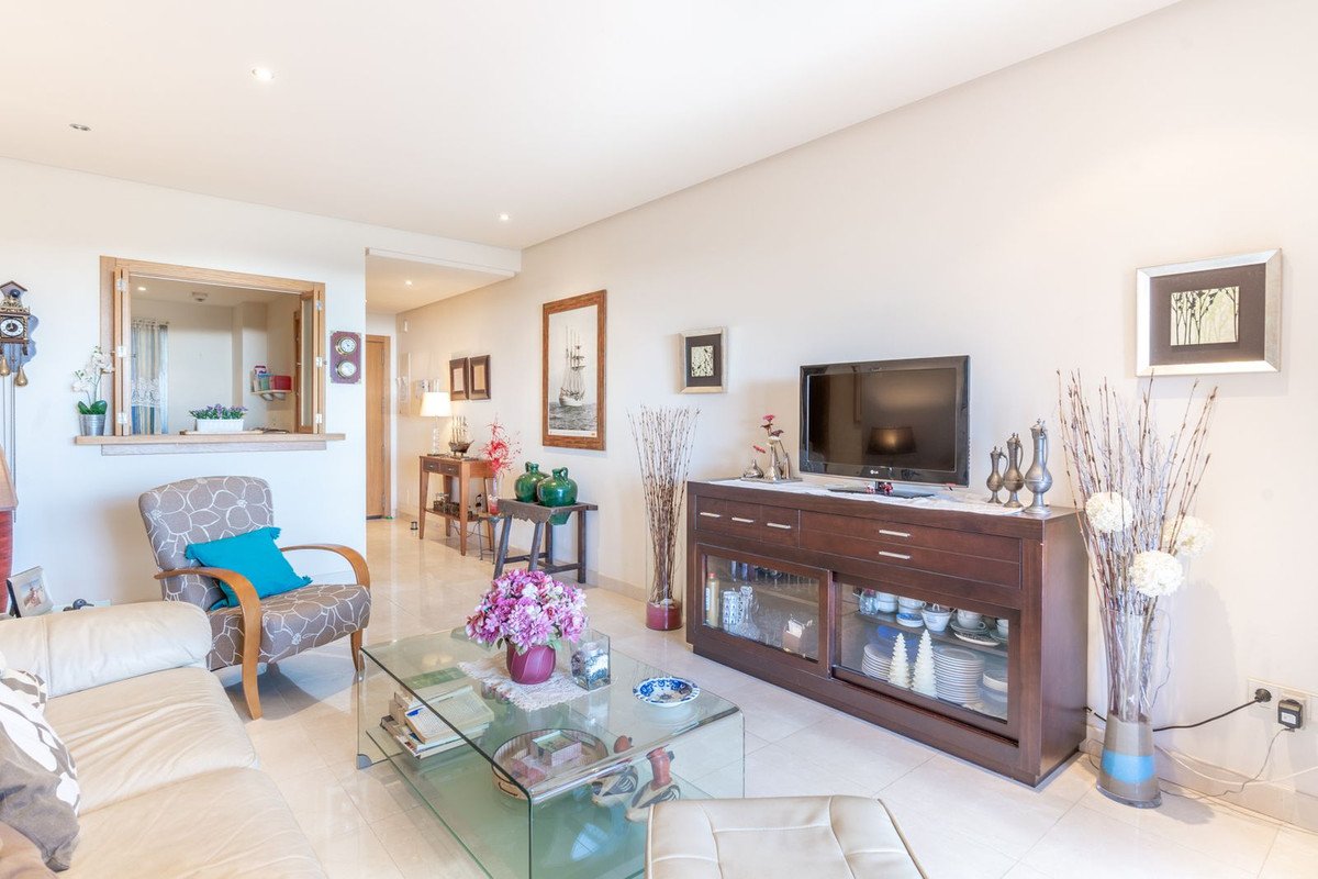 Modern living room with glass coffee table, sofa, and wooden entertainment unit.