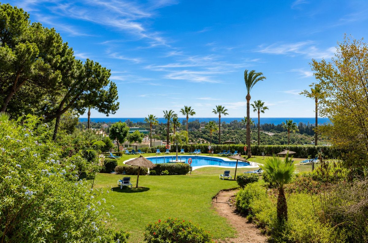 Outdoor pool with sea view surrounded by garden and palm trees