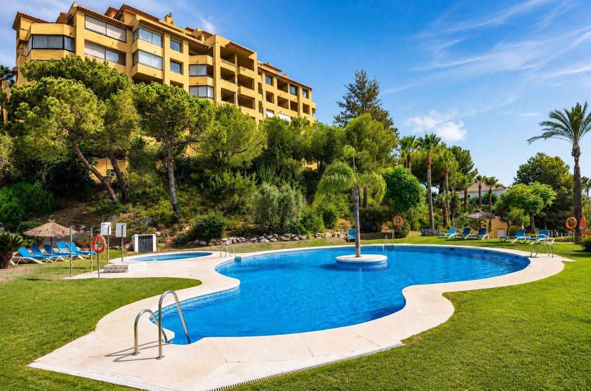 Outdoor swimming pool with lounge chairs, lawn, and resort building view