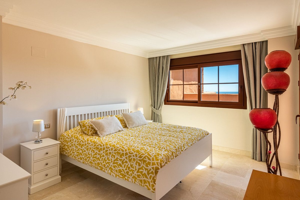 Bright bedroom with yellow bedspread, sea view through large window