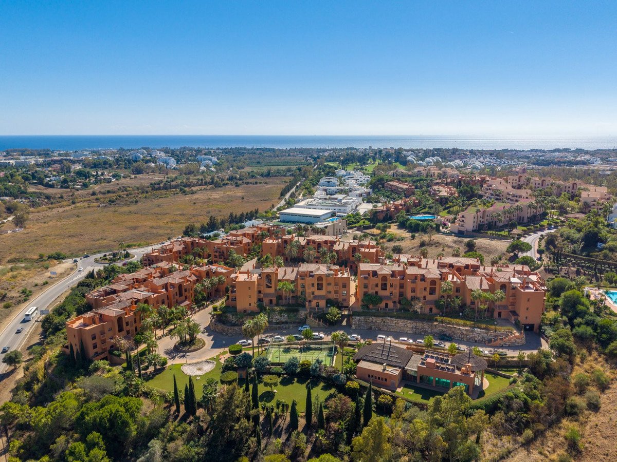 Aerial view of a terracotta apartment complex with sea view and surrounding greenery