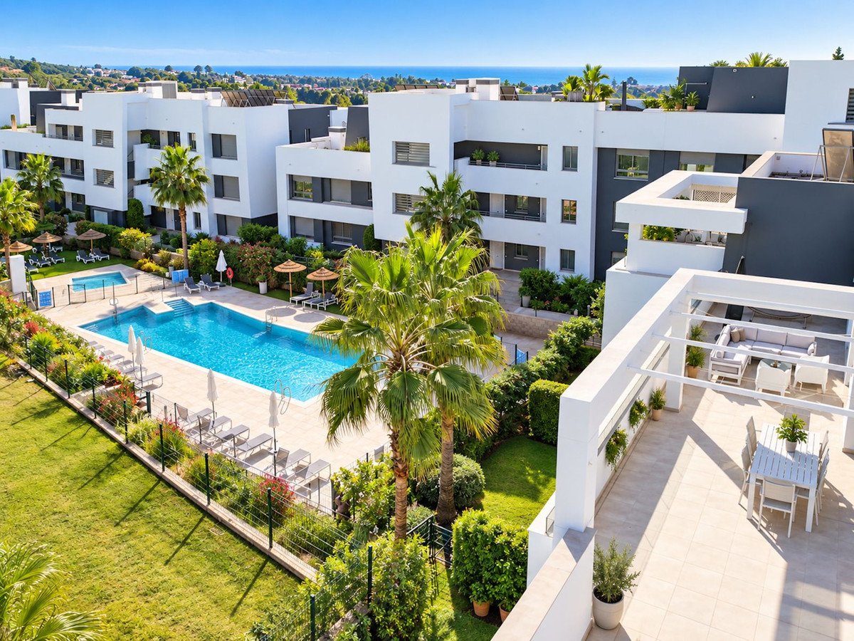 Modern apartment complex with pool, palm trees, and sea view
