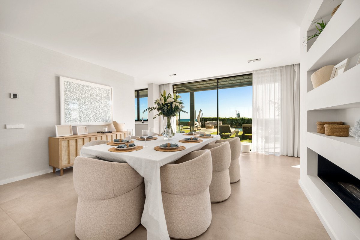 Modern dining room with ocean view, large windows, and outdoor seating area.