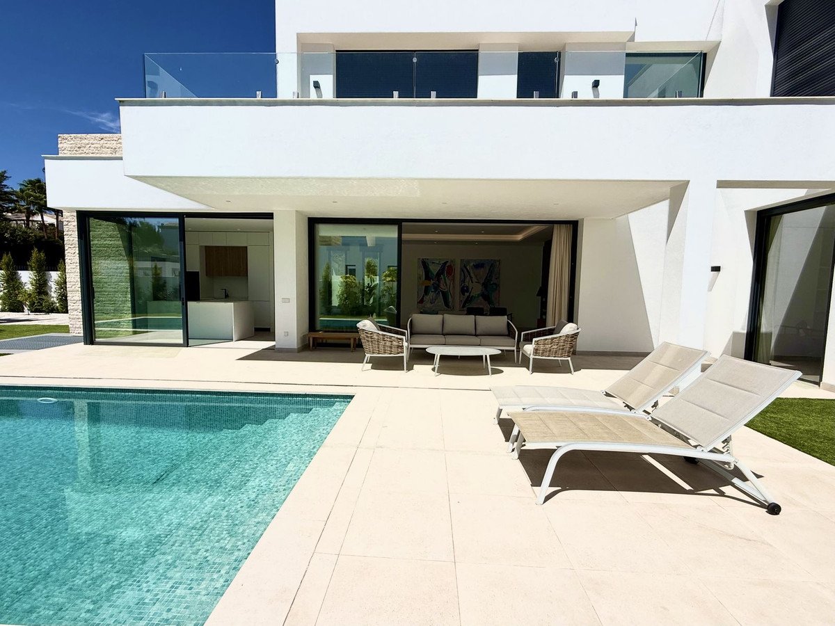 Modern villa with swimming pool, patio seating, and lounge chairs