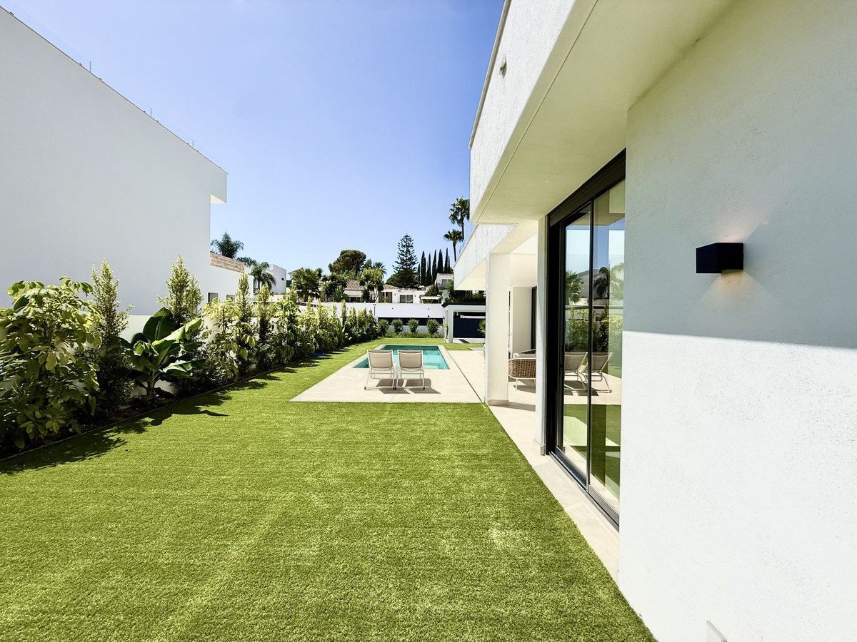 Modern backyard with green lawn, swimming pool, and outdoor seating area