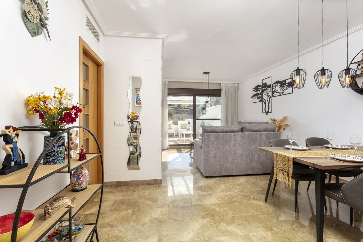 Spacious living and dining area with a comfortable sofa, dining table, and access to a sunny terrace with outdoor seating.