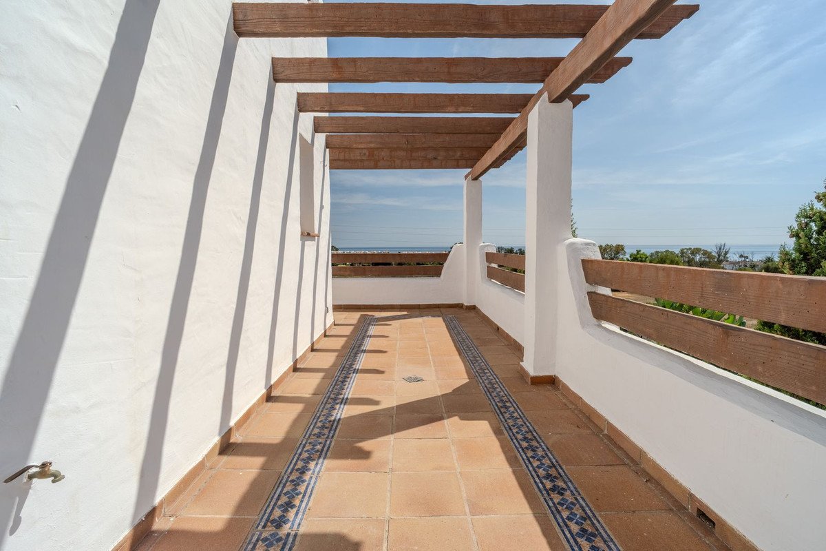 A spacious terrace with tiled floor, wooden pergola, and sea view.