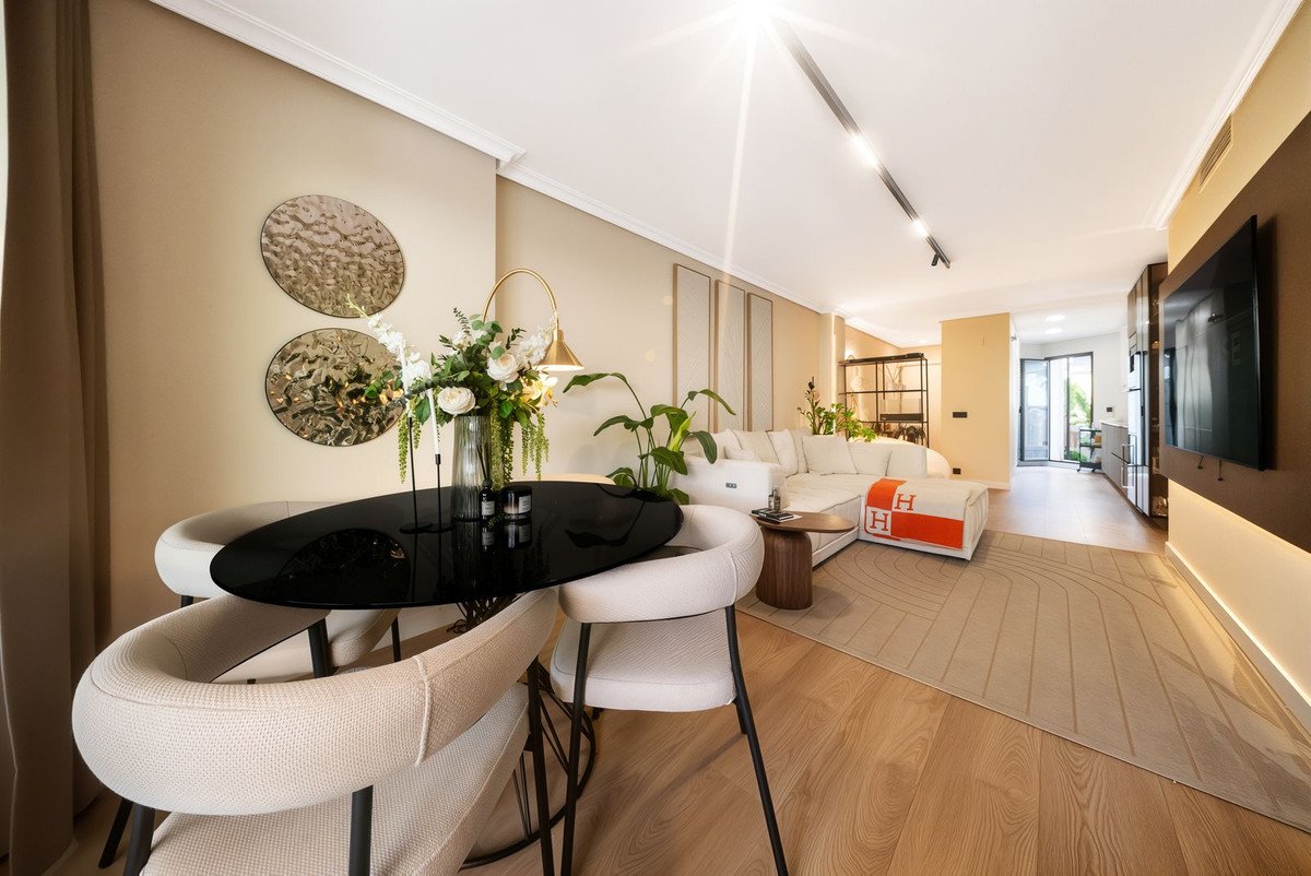 Modern living room with black dining table, white sofa, and large TV.