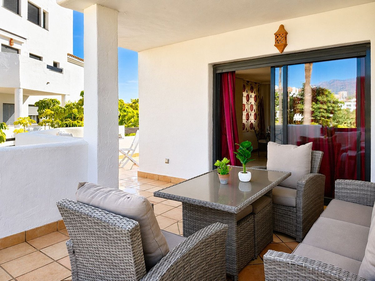 A spacious terrace with comfortable seating, a dining table, and views of lush greenery and mountains.