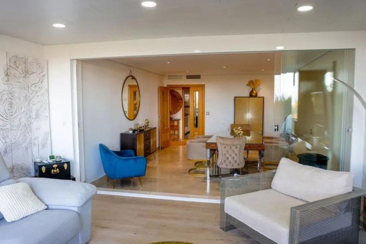Modern living and dining area with plush seating, elegant table, and decorative gold cabinet.