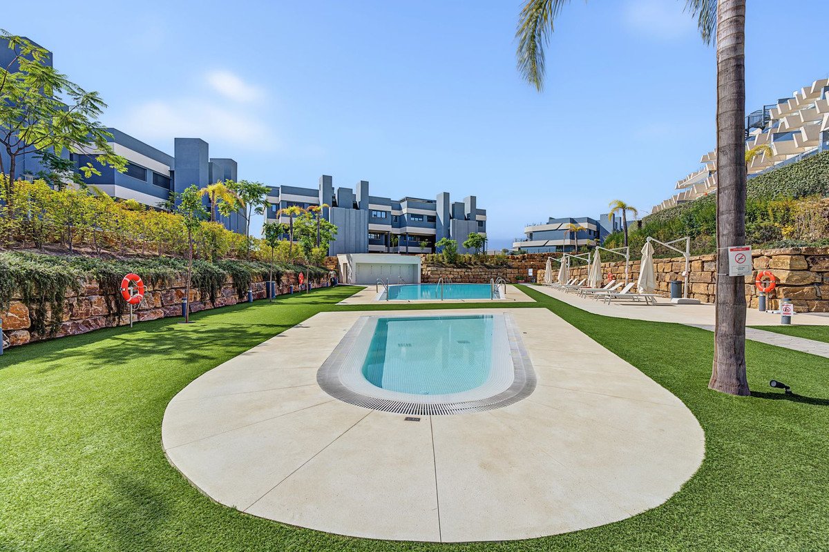 Apartment complex pool area with sun loungers and green lawn