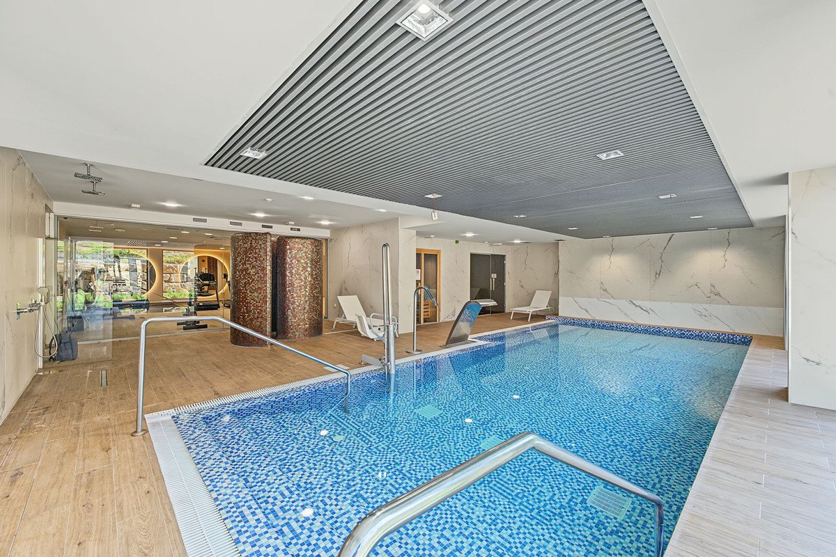 Indoor swimming pool with lounge chairs and modern ceiling design