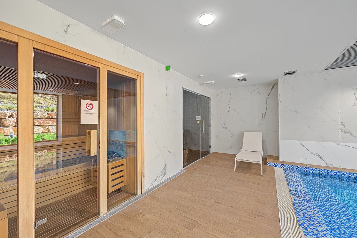 Indoor pool area with sauna, lounge chair, and marble walls