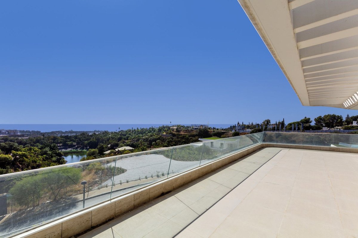Balcony with glass railing overlooking sea and green landscape