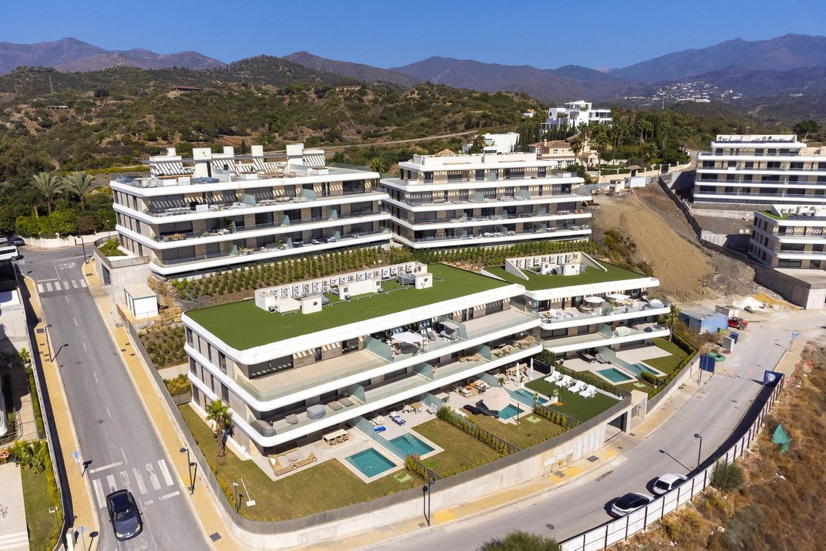 Modern apartment complex with green roofs, pools, and mountain backdrop