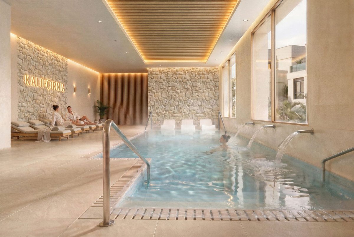 Indoor pool with stone walls, lounge chairs, and a person swimming