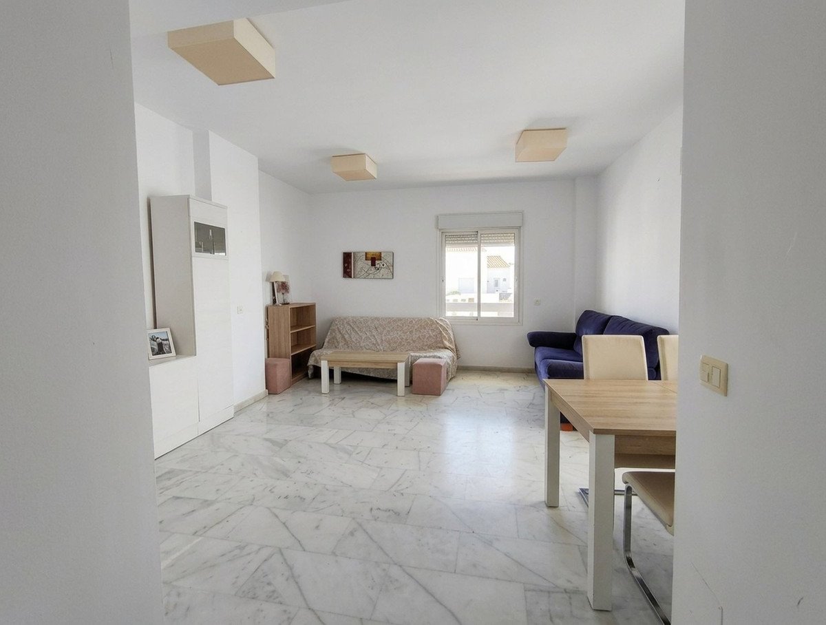 Spacious living and dining area with a blue sofa, dining table, beige sofa, and marble floors. A window offers a view of the outside.