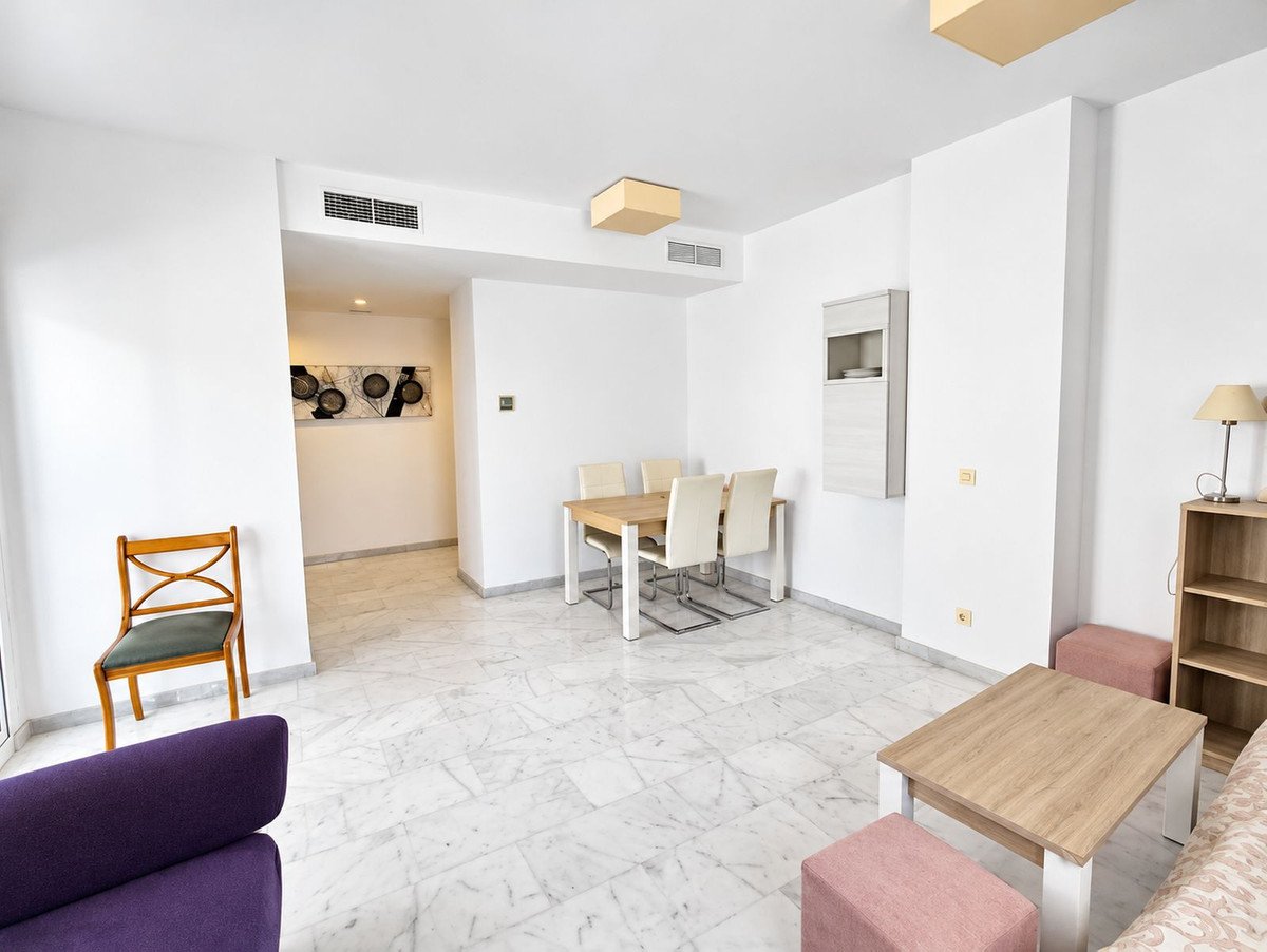 Modern living and dining area with marble floors, featuring a dining table, seating, and a bookshelf.