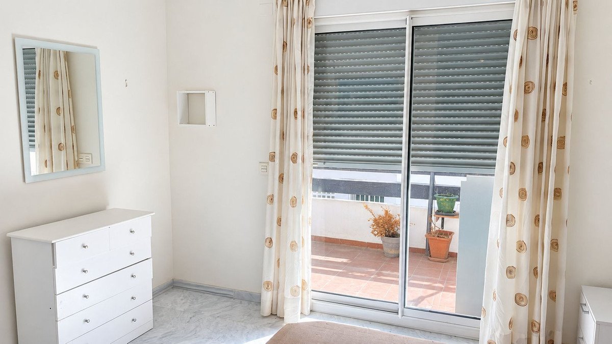 Bedroom with sliding glass doors to a balcony, white dresser, and mirror.