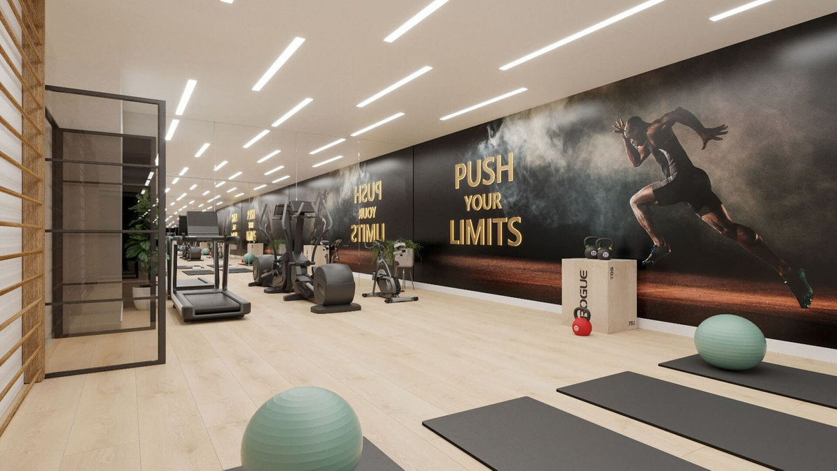 Moderne fitnessruimte in Mala Kai Estepona met diverse apparatuur en motiverende muurdecoratie.