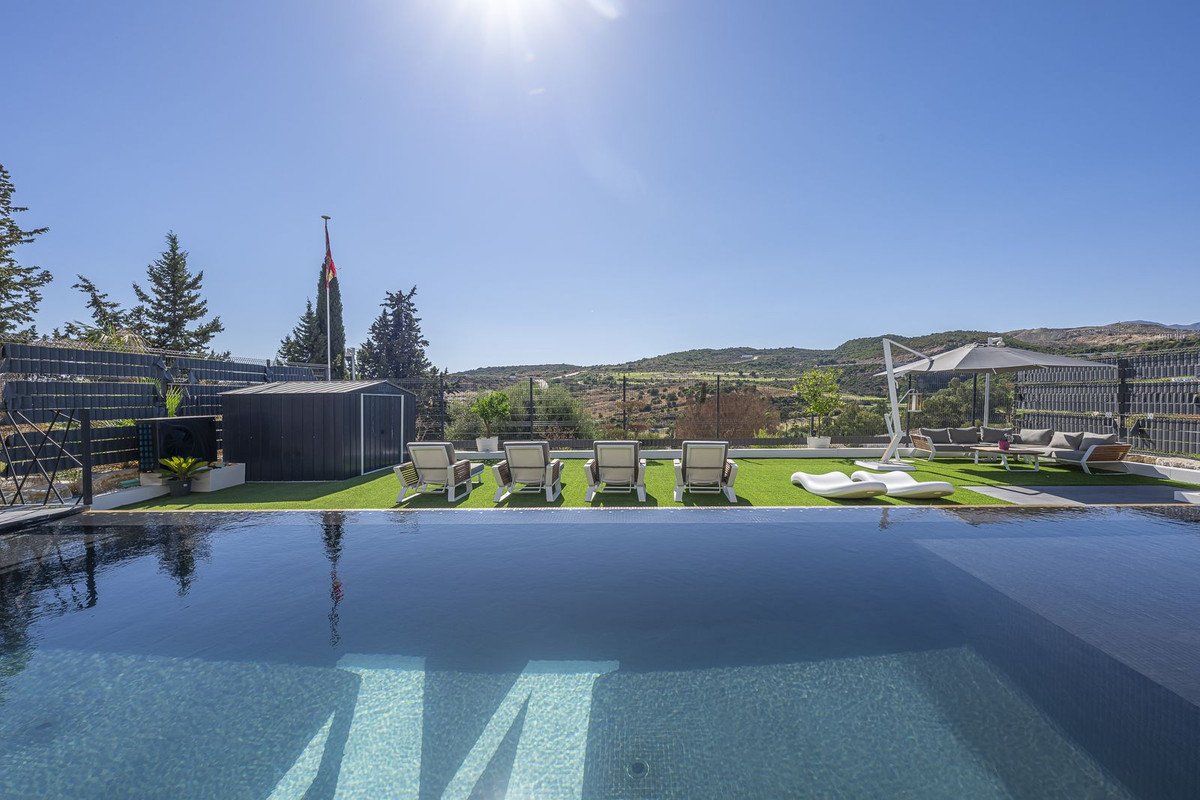 Infinity pool overlooking a serene landscape with lounge chairs and outdoor seating, perfect for relaxation.