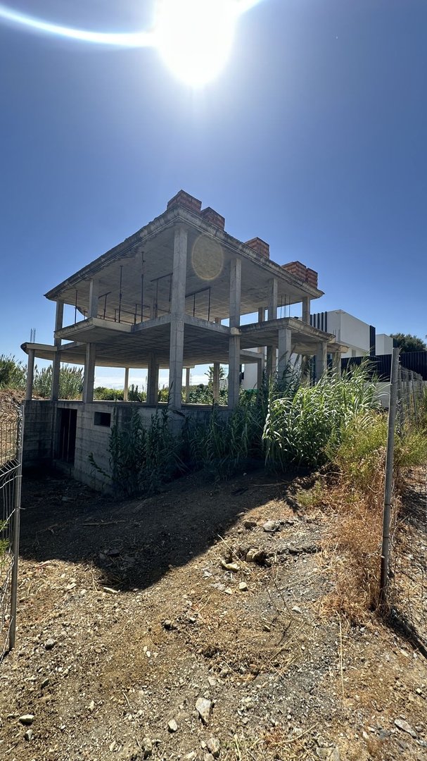 Exterior view of a three-story concrete building under construction on a sunny day.