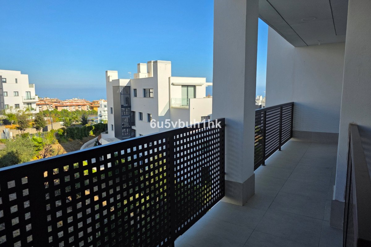 Modern balcony with black lattice railing overlooking sea and city buildings
