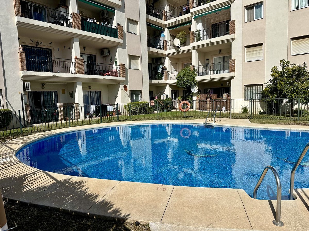 Apartment building overlooking a swimming pool with lush green surroundings and balconies.